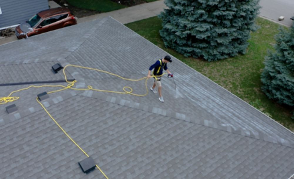 Aerial view of a Revive Your Roof technician inspecting a grey shingle roof on a Utah home