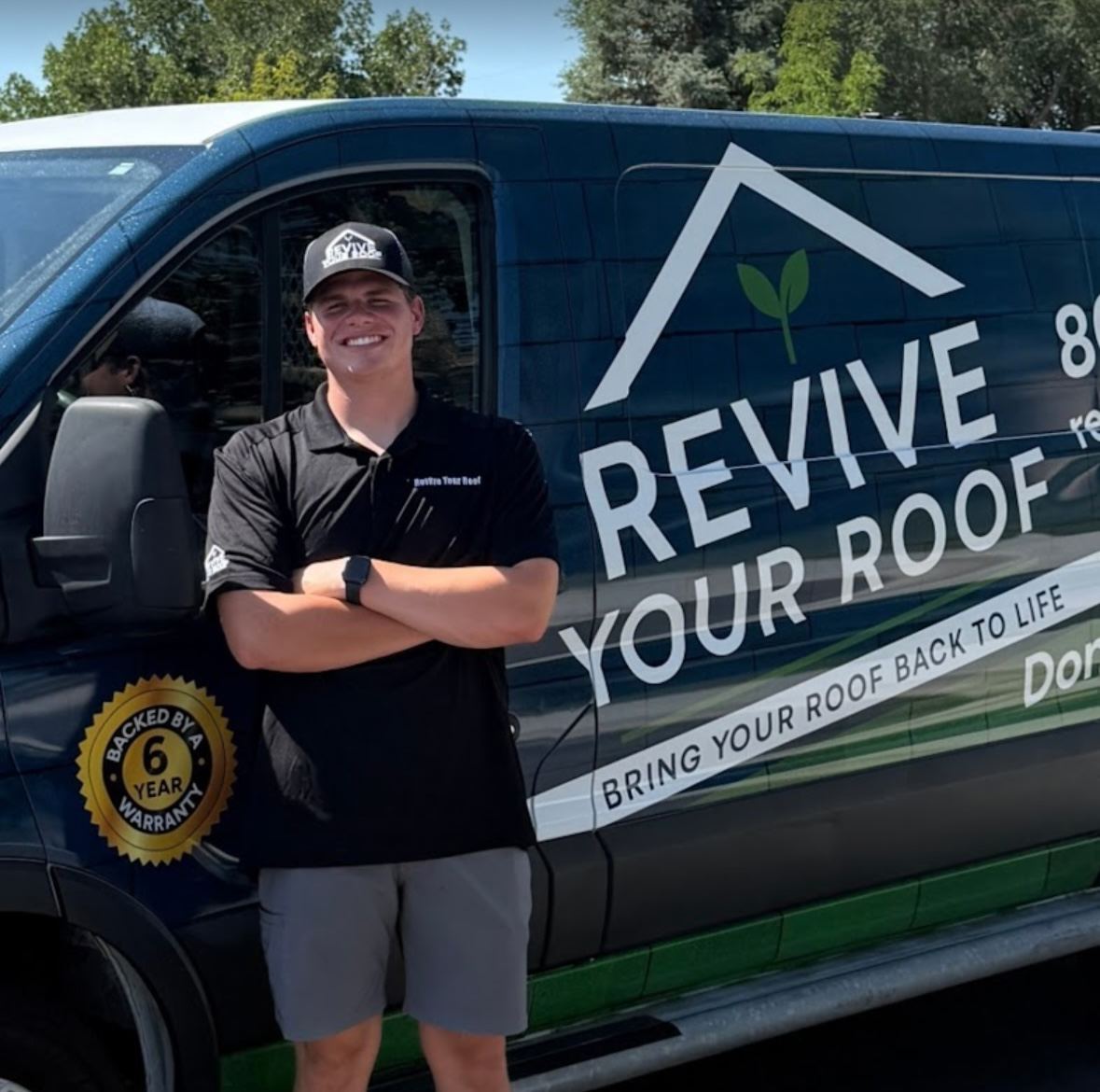 Revive Your Roof team member standing beside the branded company van, with the gold warranty badge visible on the door