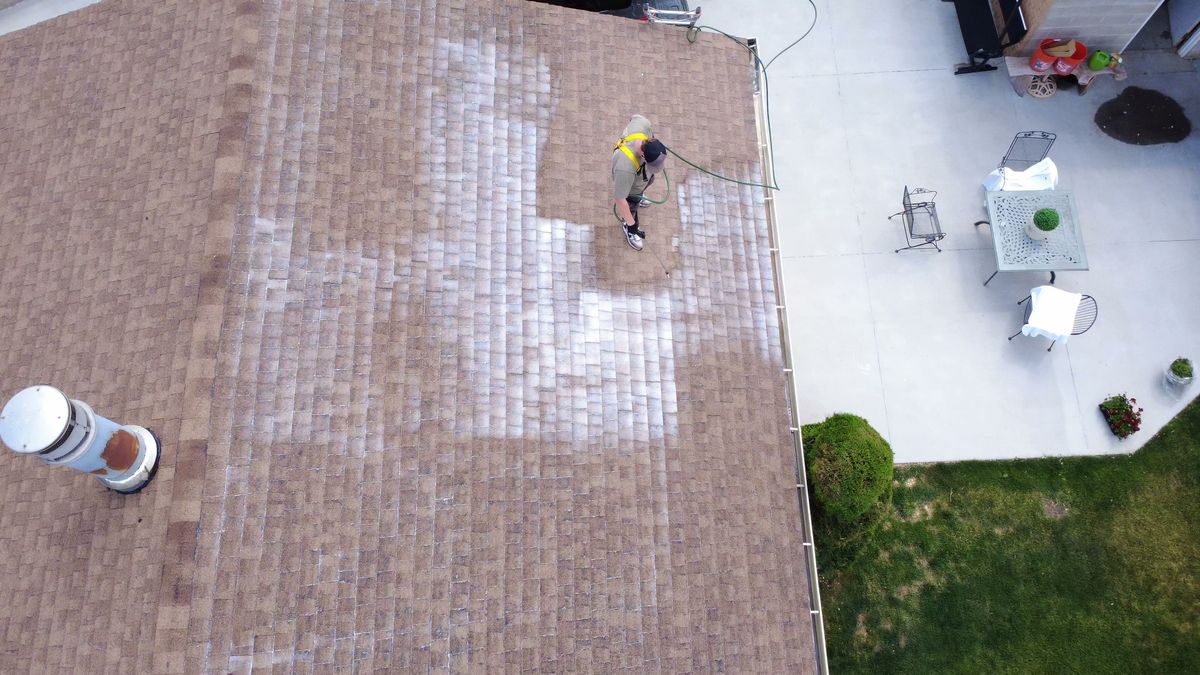 A Utah roof halfway through treatment, the treated section clearly darker than the untreated section beside it